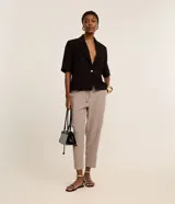 Pantalón fluido Cortelle de talle alto confeccionado en crepé, con elástico y lazo ajustable en la cintura. Presenta un diseño de estampado geométrico con patrones inspirados en tejas en tonos beige y negro.