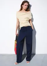 Pantalón de vestir azul marino de tiro bajo y diseño recto, con trabillas, bolsillos laterales y cierre oculto.