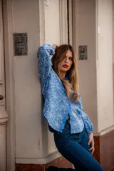 Camisa de manga larga con diseño abullonado, confeccionada en tela bordada con motivos florales. Presenta cierre frontal con botones y puños elásticos.