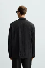 Blazer negra relaxed fit confeccionada en tejido fluido con mezcla de lyocell. Cuello con solapas de muesca y manga larga. Bolsillos de solapa en cadera. Detalle de bolsillo interior. Cierre frontal de botonadura.