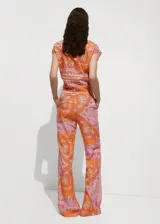 Pantalon de tiro medio con diseño acampanado y corte flare, confeccionado en tejido mezcla de lyocell y lino con estampado paisley en tonos naranja y rosado. Cuenta con cierre oculto de botón, gancho y cremallera, y bolsillos delanteros.