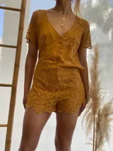 Mono corto color ocre con encaje floral, escote en V y mangas cortas.