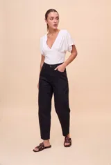 Pantalón de tiro alto y calce barrel, color negro, con piernas amplias que se afinan hacia los tobillos. Cuenta con bolsillos delanteros y traseros, presillas para cinturón y cierre frontal con botón y cremallera.