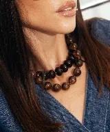 Collar de cuentas redondas y aplanadas con efecto marmolado en tonos grisáceos, con cierre metálico dorado.