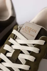 Championes urbanos de diseño técnico, combinando paneles de gamuza y tela en tono verde oliva con detalles en beige y negro. Presentan una suela de plataforma en color crema con base dentada en tono caramelo.