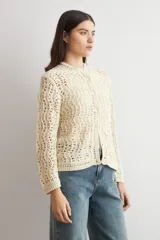 Cardigan de punto calado color beige, con cuello redondo y cierre frontal de botones.