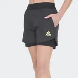 Short de running para mujer de Le Coq Sportif, color negro, con diseño de doble capa: una capa exterior ligera y una capa interior tipo calza. Presenta cintura elástica ancha y el logo del gallo en dorado en el muslo izquierdo.