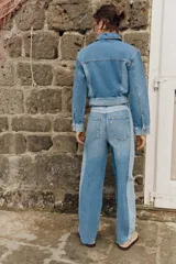 Jeans de tiro medio con diseño barrel y paneles laterales en un tono de denim más claro que contrasta con el centro. Presenta cinco bolsillos, cierre frontal con cremallera y botón, y bajo con acabado sin costura.