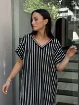 Vestido largo de tejido a rayas verticales blancas y negras, con escote en V y tajos laterales.
