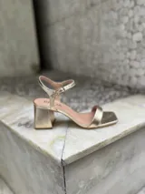 Sandalias negras de tacón bajo y ancho, con punta cuadrada, talón abierto y tira fina ajustable al tobillo.