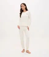 Pijama largo de mujer confeccionado en tejido peach touch, compuesto por una blusa de cuello redondo y manga larga con pequeño bordado en el pecho, y un pantalón con cintura elástica. Presenta un sutil estampado de cuadros.