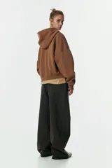 Campera con capucha de corte holgado y diseño cropped, confeccionada en felpa con interior cepillado. Presenta cierre frontal, hombros caídos, bolsillos tipo parche y terminaciones en punto acanalado en puños y bajo.