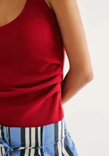 Musculosa de tela acanalada con cuello redondo y pliegues laterales que aportan textura y un ajuste entallado al cuerpo.