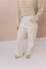 Pantalón de jean de tiro medio-alto y pierna amplia con caída recta, color amarillo manteca, con diseño clásico de cinco bolsillos y cierre delantero con botón.