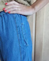 Pantalón de algodón color arena, de corte recto y holgado, con cintura elástica y detalle de costuras horizontales decorativas en la parte inferior de las piernas.