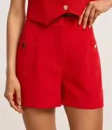 Short sastre de cintura alta con estructura definida, bolsillos laterales decorados con tachuelas metalizadas y recortes delanteros con costura aparente.