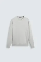 Jersey color crudo de tejido de punto, con cuello redondo y mangas largas. Corte amplio y terminaciones en rib.