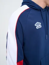 Canguro deportivo Umbro del Club Nacional de Football, modelo Nexo para hombre. Diseño en color azul marino con mangas rojas y detalles en celeste y blanco, capucha con cordón ajustable y bolsillo tipo canguro.