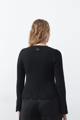 Top de tejido acanalado con sutil acabado metalizado, de silueta entallada con diseño peplum en la cintura y mangas largas levemente acampanadas.