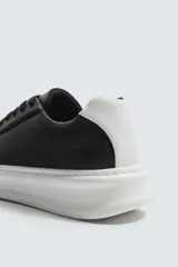 Zapatillas deportivas blancas de caña baja, con detalle de color negro en el talón y suela con volumen.