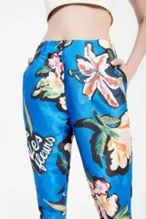Pantalón sastre azul con estampado de flores y texto en blanco. Tiro alto, corte relajado, cintura pinzada y pierna recta.
