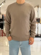 Buzo de hilo color beige claro, con cuello redondo y diseño clásico de manga larga.