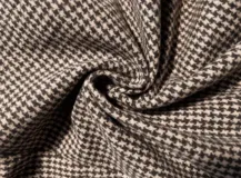 Chaqueta corta de corte recto con estampado de cuadros pequeños en tonos marrones y beige. Presenta cuello alto, mangas largas y cierre frontal oculto.