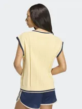 Chaleco tejido de punto color amarillo claro, con cuello en V y detalles en azul marino en el cuello, sisas y ruedo. Presenta diseño trenzado y corte holgado.