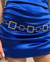 Cinturón de cadena metálica dorada compuesto por eslabones cuadrados de textura rugosa intercalados con eslabones cuadrados lisos más pequeños.