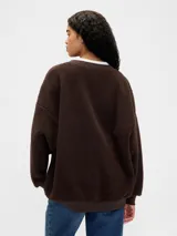 Buzo de corderito color blanco, con cuello redondo, mangas largas y logo de la marca bordado en el frente.