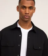 Camisa manga larga de sarga en color verde militar, con cuello inglés, cierre frontal de botones negros y dos bolsillos con solapa en el pecho.