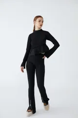 Calzas negras de tiro alto, corte ajustado y botamanga acampanada con cierre metálico en el tobillo.