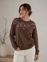 Sweater de punto color marrón, con cuello redondo, mangas largas y calce relajado. Presenta un delicado diseño bordado con brillos en forma de hojas sobre el escote y los hombros.