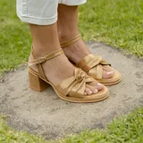 Sandalias de cuero color dorado, con plataforma y taco cuadrado. Presentan tiras cruzadas en el empeine y pulsera al tobillo con hebilla.