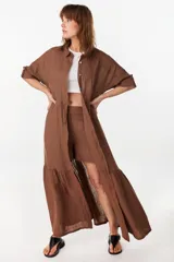Vestido camisero largo de lino italiano color celeste, de corte relajado, con mangas caídas, jareta ajustable en la cintura, cierre frontal de botones y bajo con volado fruncido.