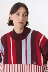 Buzo de tejido de punto con diseño de bloques de rayas verticales en colores rojo, verde, bordó y crema. Presenta cuello alto, corte oversize y terminaciones en rib en puños y ruedo.