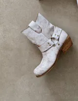 Bota estilo tejana de cuero vacuno color bordó, con detalle de argolla metálica y remaches decorativos.
