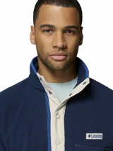 Polar Columbia Helvetia Half Snap azul marino, confeccionado en tejido suave de borreguito, con cuello alto, cierre frontal de botones a presión con solapa en tono beige y un bolsillo con cierre en el pecho con el logo de la marca.