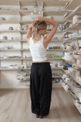Pantalón negro de corte holgado y diseño abombacho, con cintura elástica fruncida, costuras decorativas y paneles en la parte inferior.