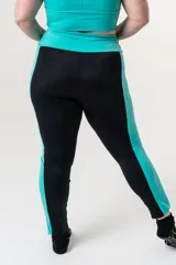 Calza deportiva de tiro alto con cintura elástica reforzada. Presenta un diseño bicolor que combina paneles laterales y faja con estampado animal print en tonos coral y turquesa sobre una base negra.