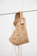 Faja de cuero vacuno color beige, con diseño de calados geométricos, costuras decorativas y cierre frontal con hebilla metálica.