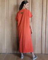 Vestido largo color crema, de corte recto y holgado, con cuello redondo y mangas cortas. Presenta aberturas laterales en la falda.