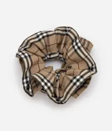 Scrunchie para el cabello con diseño fruncido y volumen estructurado, confeccionado en tela con estampado de cuadros escoceses en tonos beige, negro y blanco.