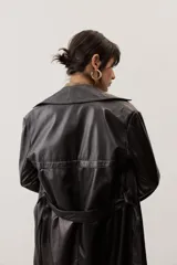 Chaqueta negra de cuero con cuello camisero, mangas largas y costuras decorativas.