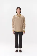 Sweater de punto color marrón con cuello polo en contraste color crema. Presenta diseño de rayas verticales texturizadas, mangas largas con puños en color crema y corte holgado.