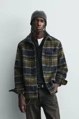 Sobrecamisa de corte relajado confeccionada en tejido con textura efecto pelo. Presenta diseño de cuadros en tonos verde y negro, cuello solapa, cierre frontal con botones, manga larga con puños abotonados y un bolsillo de plastrón en el pecho.