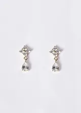 Aros colgantes de plata 925 con baño de oro 18k, formados por un diseño floral superior de circonias y un dije colgante en forma de gota con piedra transparente.
