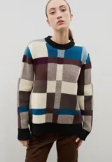 Sweater de punto con diseño jacquard a cuadros en tonos azul, marrón, crema y negro. Presenta cuello redondo, puños y ruedo acanalados, con un corte holgado y cómodo.