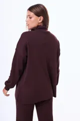 Buzo tejido de punto color negro, con cuello alto, manga larga y corte holgado con aberturas laterales en el ruedo.