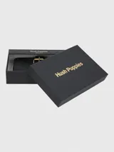Billetera de cuero natural color negro con diseño de hebilla decorativa frontal en tono dorado. Cuenta con cierre perimetral, múltiples ranuras para tarjetas, compartimento para billetes y tecnología de protección RFID.